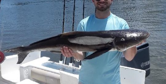 Man on Boat Holding Fish